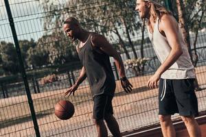 Another round Two young men in sports clothing playing basketball while spending time outdoors photo