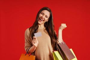 mujer joven feliz con ropa informal que lleva bolsas de compras y tarjeta de crédito foto