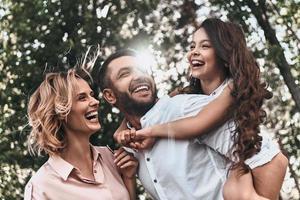 Lazos familiares. feliz familia joven de tres sonriendo mientras pasa tiempo libre al aire libre foto