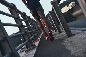 Free run. Close up rear view of young man in sports clothing jogging while exercising outdoors photo