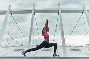 Balancing her mind and body. Modern young woman in sports clothing stretching while warming up outdoors photo