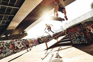 Getting some air. Three young men skateboarding at the skate park together photo