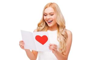 Valentine card from him. Beautiful young blond hair woman holding valentine card and smiling while standing isolated on white photo
