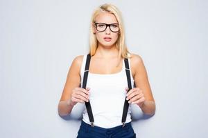 Piercing glance. Beautiful young blond hair women looking at camera and posing while standing against grey background photo