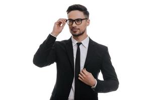 Always perfect. Handsome young man in full suit adjusting his jacket and looking away while standing against white background photo