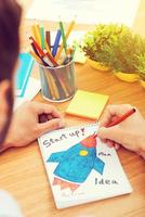 Starting new great project. Close-up top view of man sketching while sitting at the wooden desk photo