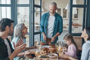 Happy multi-generation family communicating and smiling while having dinner together photo