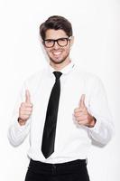 Used to success. Confident young man showing his thumbs up and smiling while standing against white background photo