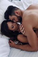 Hot moments. Top view of beautiful young couple making love while lying in the bed photo