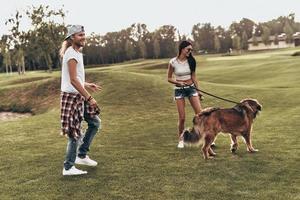 He is more than just a pet. Full length of beautiful young couple playing with their dog while spending time outdoors photo
