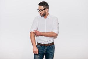 Ready to work. Confident mature man in white shirt adjusting his sleeve while standing against white background photo