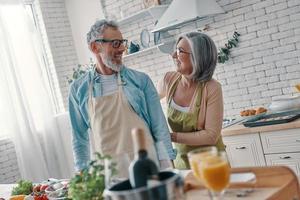 Joyful senior couple preparing to cook a dinner and smiling while spending time at home photo