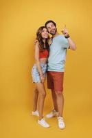 Full length of beautiful young couple smiling while standing against yellow background photo