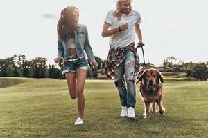 True joy of just being around. Full length of modern young couple playing with their dog while spending free time in the park photo