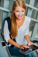 Technologies makes study easier. Top view of smiling young woman holding digital tablet and looking at camera while sitting on the stairs photo