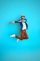 Full length of playful young man dancing while hovering against blue background photo