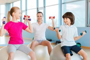 Living a healthy life. Mother and two children exercising in health club and smiling photo