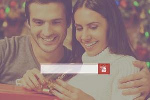 Presents search. Happy young woman opening a gift box while her boyfriend sitting close to her and smiling with Christmas decoration in the background photo