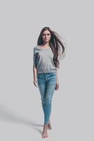 Confident and beautiful. Full length studio shot of attractive young woman in casual wear walking and looking at you photo