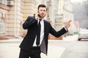 On the way to work. Handsome young man in formalwear stretching out hand with thumb up while standing on the road photo