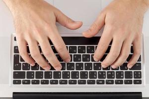 Working on computer. Top view of hands typing something on computer keyboard photo