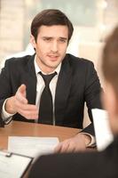 Business conversation. Two business people in formalwear discussing something while sitting at the table photo