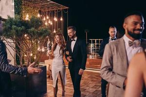 Group of people in formalwear communicating and smiling while spending time on luxury party photo
