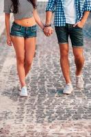 Walking together. Close-up of young loving couple holding hands while walking along the street photo