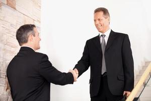 Handshake. Two business men in formalwear handshaking on staircase and smiling photo