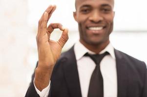 Successful businessman. Cheerful young African man in formalwear gesturing and smiling at camera photo