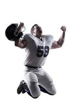Wild emotions.  American football player screaming and keeping arms raised while kneeling against white background photo