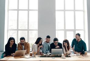 equipo exitoso grupo de jóvenes modernos con ropa informal inteligente usando tecnologías modernas mientras trabajan en la oficina creativa foto