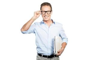 Confident IT expert. Happy mature man in shirt holding laptop and adjusting his eyeglasses while standing against white background photo