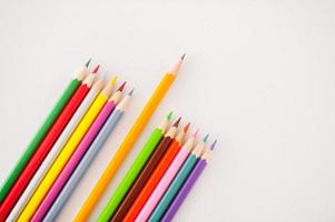 Thinking outside the box. Top view of one simple pencil laying between multi colored pencils photo