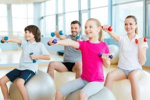 Exercising together is fun. Happy sporty family exercising in sports club together photo