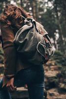 vista trasera de una mujer con mochila subiendo mientras camina por el bosque foto