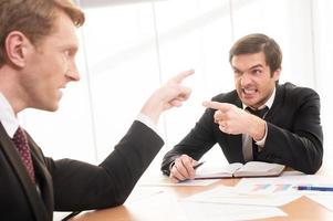 Business confrontation. Two young men in formalwear arguing and pointing each other photo