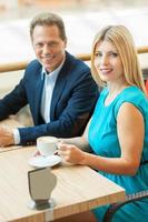 pareja en cafetería. vista superior de una hermosa pareja madura tomando café juntos y mirando la cámara mientras se sienta en la cafetería foto