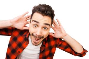 Shocking news. Portrait of surprised young man in shirt smiling while standing against white background photo