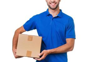 su paquete está en buenas manos. imagen recortada de un joven mensajero sosteniendo una caja de cartón y sonriendo mientras se enfrenta a un fondo blanco foto