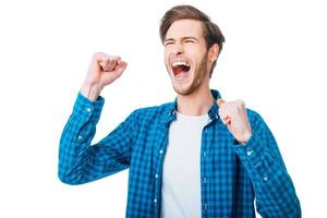 The win is in my pocket. Excited young man keeping arms raised and expressing positivity while standing against white background photo