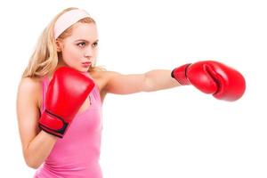 boxeo rubio. mujer de cabello rubio concentrado en camisa rosa y guantes de boxeo mientras está de pie aislado sobre fondo blanco foto