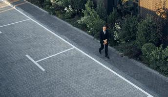 Top view of mature man in full suit carrying laptop while walking outdoors photo