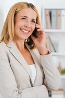 Business talk. Beautiful mature businesswoman talking on the mobile phone and smiling photo