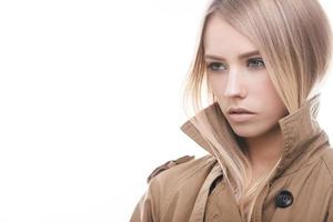 belleza en estilo otoño. retrato de una atractiva joven con abrigo mirando hacia otro lado mientras se enfrenta a un fondo blanco foto