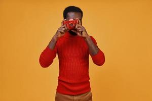 Handsome young African man in casual clothing photographing by camera photo