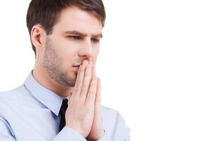 Worried about his business. Frustrated young man in formalwear holding hands clasped near mouth and looking away while standing isolated on white photo