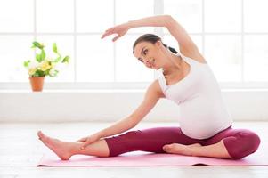 Pre-natal exercises. Beautiful pregnant woman exercising while sitting in lotus position photo