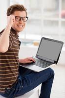encontrar un buen lugar para trabajar. vista trasera de un joven alegre que trabaja en una laptop y mira por encima del hombro foto