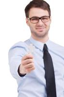 hombre con elemento de rompecabezas. joven alegre con ropa formal estirando un elemento de rompecabezas y sonriendo mientras está de pie aislado en blanco foto